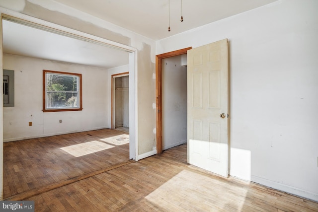 empty room featuring electric panel and light wood-type flooring