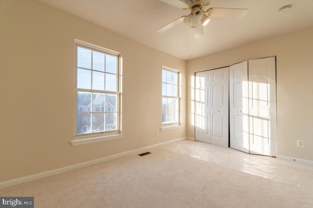 unfurnished bedroom with light colored carpet, a closet, and ceiling fan