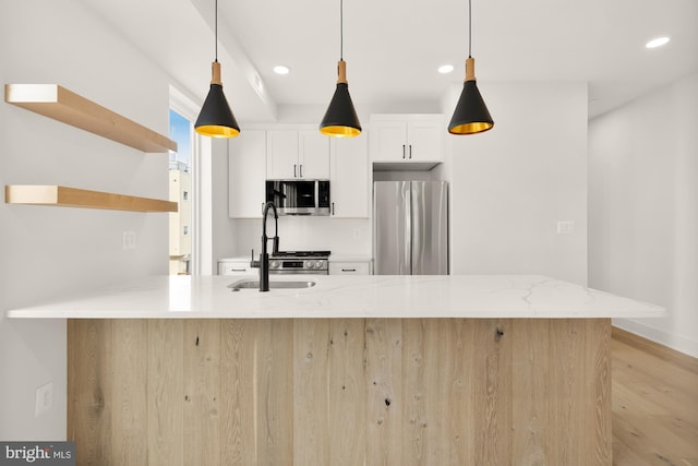 kitchen with white cabinetry, stainless steel appliances, pendant lighting, light stone counters, and sink