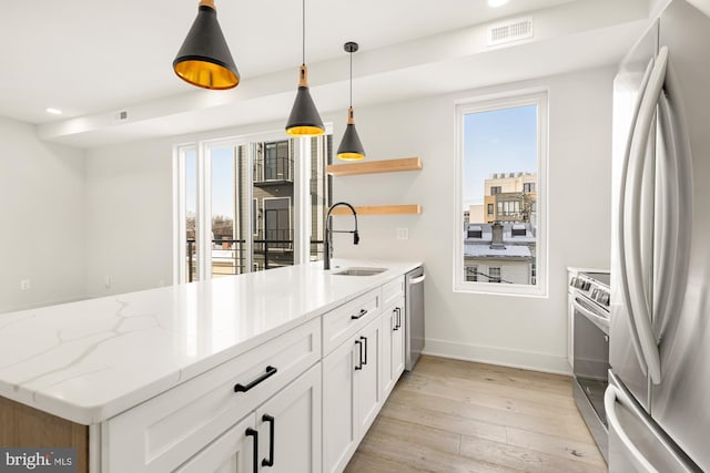 kitchen with white cabinetry, stainless steel appliances, pendant lighting, light stone counters, and sink