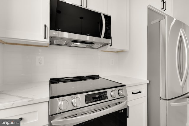 kitchen featuring light stone counters, backsplash, white cabinetry, and appliances with stainless steel finishes