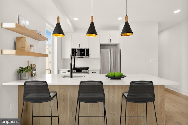 kitchen with light stone countertops, white cabinets, appliances with stainless steel finishes, a kitchen breakfast bar, and kitchen peninsula