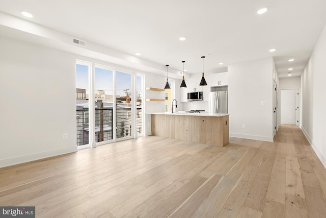 kitchen featuring stainless steel appliances, white cabinets, hanging light fixtures, light hardwood / wood-style flooring, and sink