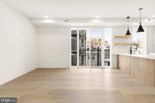 bar featuring decorative light fixtures, light hardwood / wood-style floors, and sink