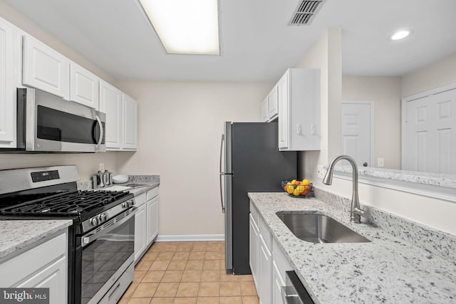 kitchen featuring sink, stainless steel appliances, white cabinetry, and light tile patterned floors