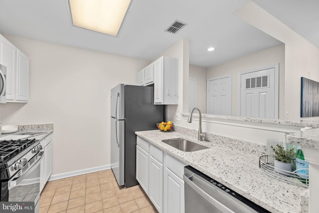 kitchen with white cabinets, stainless steel appliances, light stone countertops, light tile patterned floors, and sink