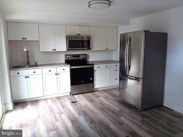 kitchen with stainless steel appliances, white cabinetry, sink, and backsplash