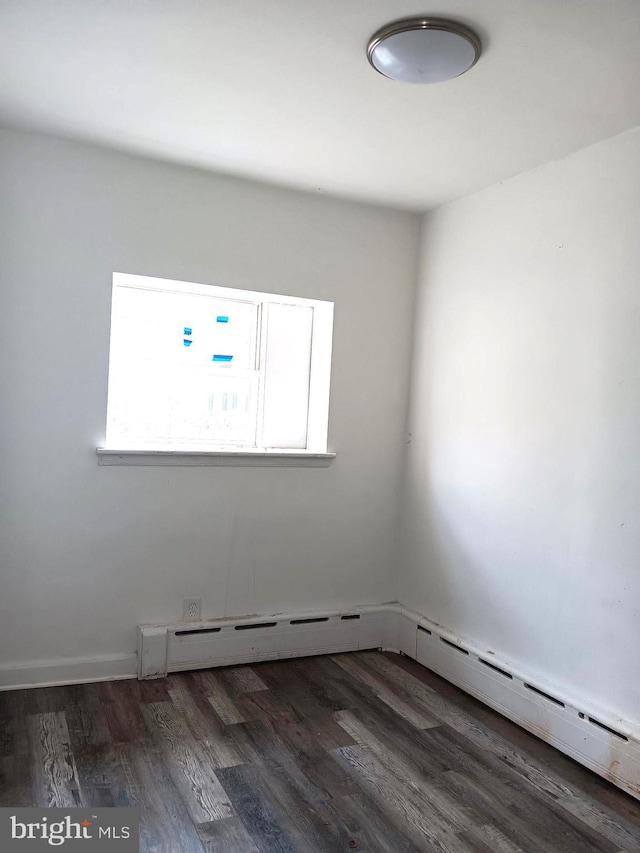 spare room with dark wood-type flooring and a baseboard radiator