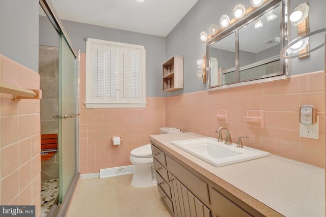 bathroom featuring toilet, vanity, tile walls, tile patterned floors, and a shower with door