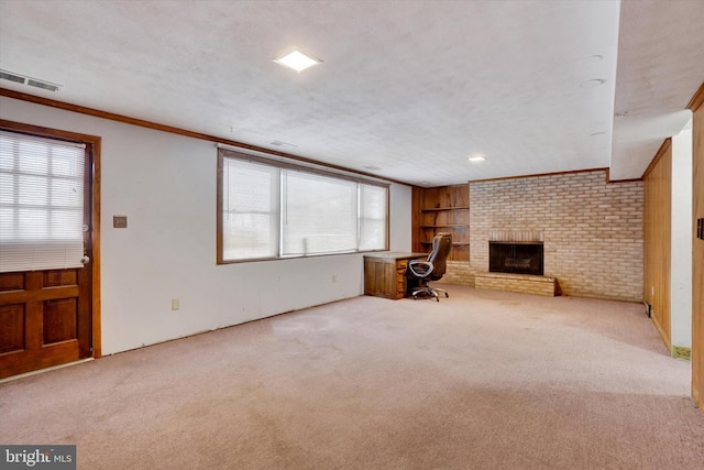 unfurnished living room with a textured ceiling, light carpet, built in features, ornamental molding, and a brick fireplace