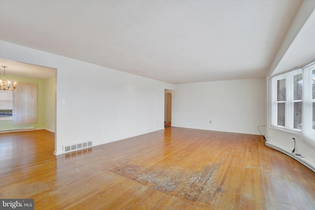 unfurnished room featuring an inviting chandelier and hardwood / wood-style floors