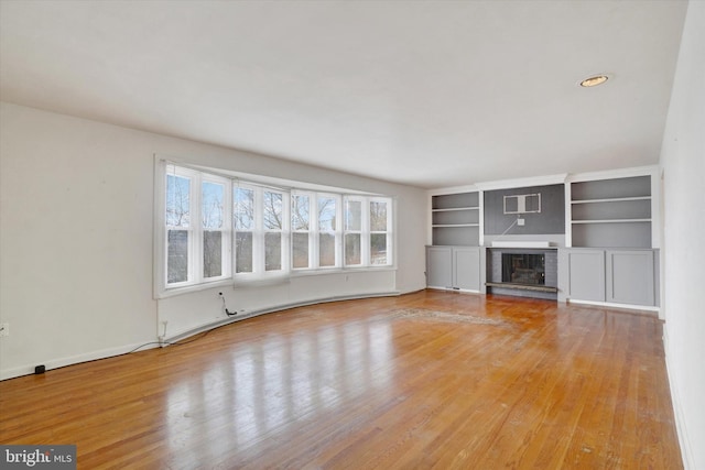 unfurnished living room with a brick fireplace and light wood-type flooring