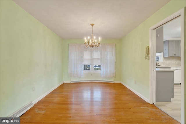 unfurnished dining area with a notable chandelier and light hardwood / wood-style flooring