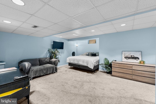 carpeted bedroom featuring a drop ceiling