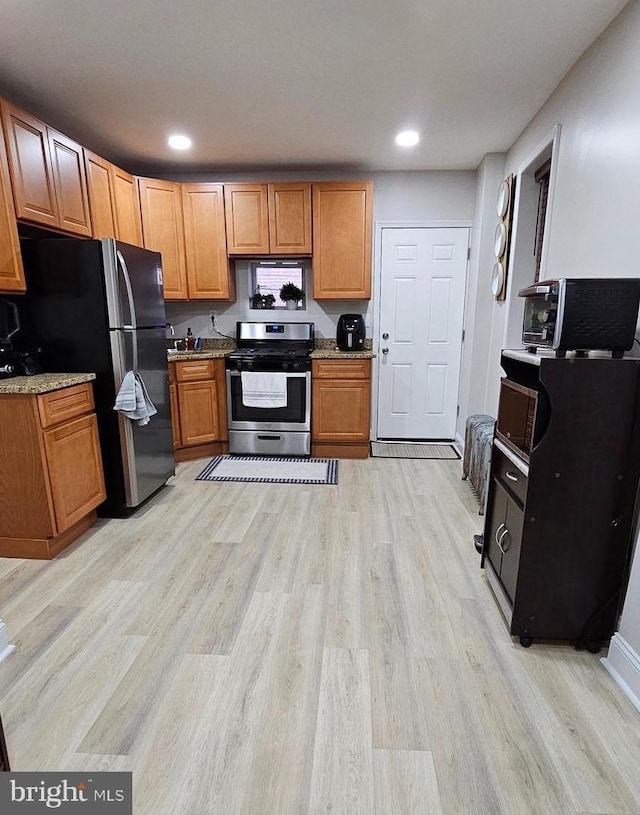 kitchen with light hardwood / wood-style floors, stainless steel appliances, and light stone counters