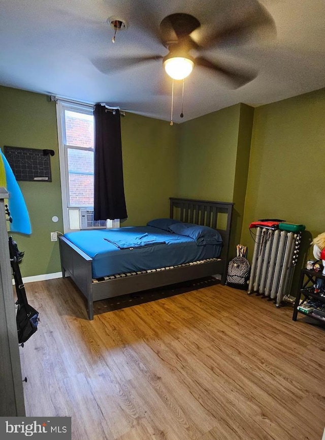 bedroom featuring hardwood / wood-style flooring, a textured ceiling, ceiling fan, and radiator