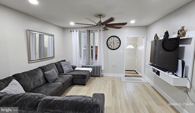 living room with light wood-type flooring, ceiling fan, and radiator heating unit