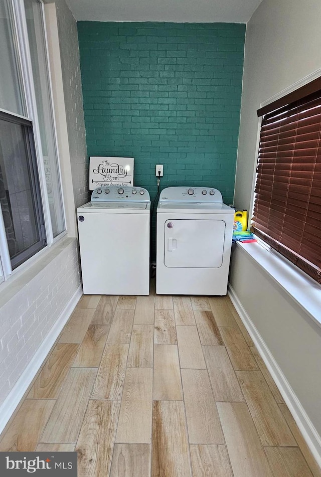 laundry room featuring washer and dryer and brick wall