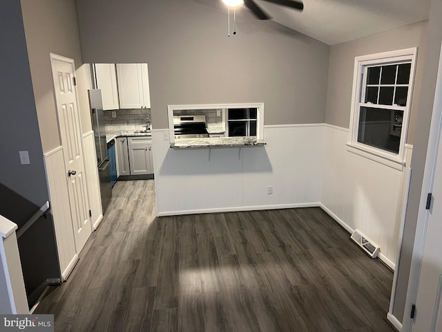 kitchen with appliances with stainless steel finishes, kitchen peninsula, a breakfast bar, dark hardwood / wood-style floors, and white cabinets