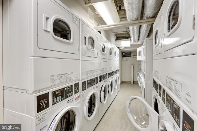 laundry area with stacked washer / drying machine and washing machine and dryer