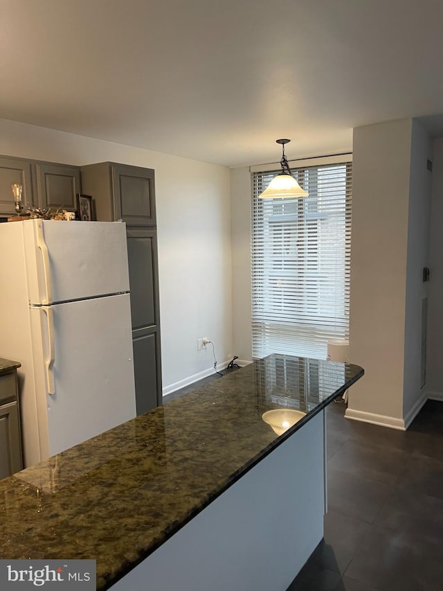 kitchen with white refrigerator, dark stone countertops, and decorative light fixtures