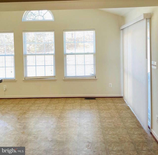 empty room with light tile patterned floors and a healthy amount of sunlight