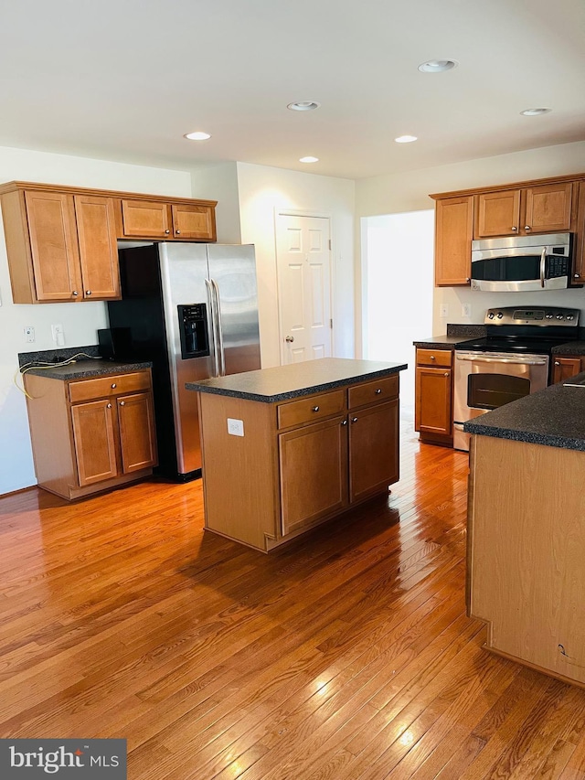 kitchen with light hardwood / wood-style flooring, a kitchen island, and appliances with stainless steel finishes