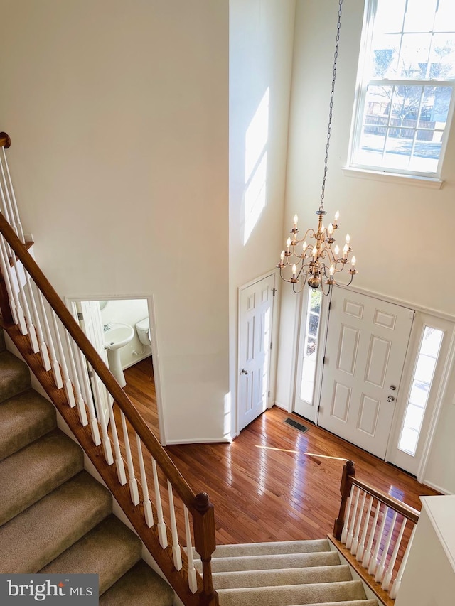 entryway featuring a high ceiling, hardwood / wood-style flooring, a wealth of natural light, and a chandelier