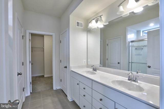 bathroom with a shower with shower door, vanity, and tile patterned flooring