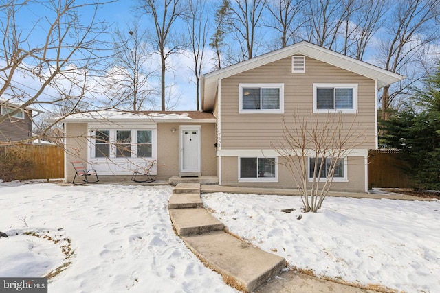 split level home with fence and brick siding