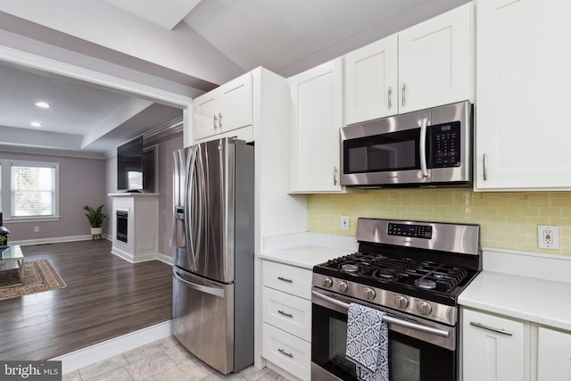 kitchen featuring stainless steel appliances, backsplash, light countertops, and white cabinetry