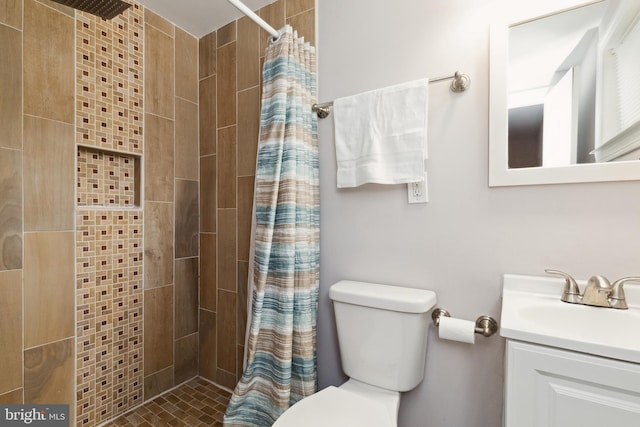 bathroom featuring toilet, tiled shower, and vanity