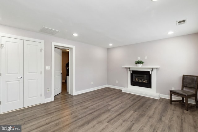 interior space with a glass covered fireplace, visible vents, and wood finished floors