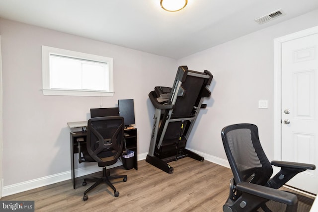 office space with light wood-type flooring, visible vents, and baseboards