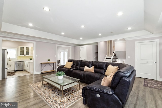 living area featuring light wood-style flooring, recessed lighting, stairway, a tray ceiling, and crown molding