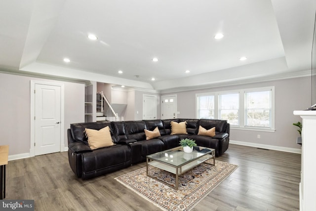 living room with recessed lighting, wood finished floors, baseboards, stairs, and a raised ceiling