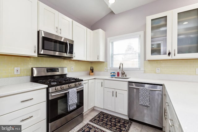 kitchen with stainless steel appliances, decorative backsplash, a sink, and white cabinets