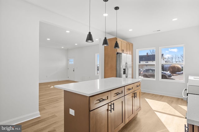 kitchen with light hardwood / wood-style flooring, light brown cabinetry, stainless steel refrigerator with ice dispenser, a kitchen island, and pendant lighting