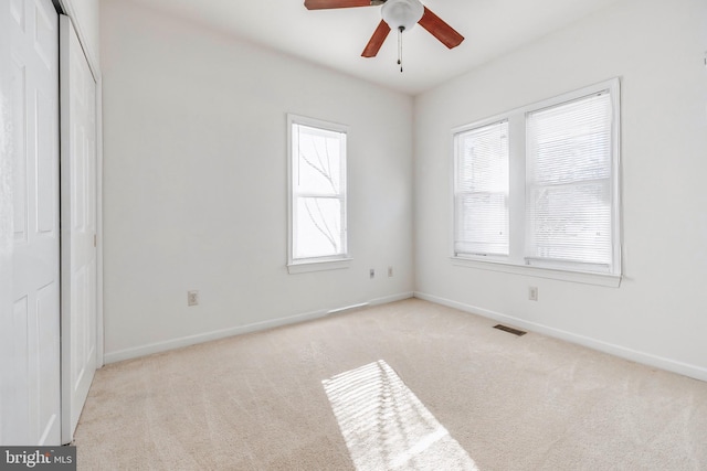 carpeted empty room featuring ceiling fan and a wealth of natural light