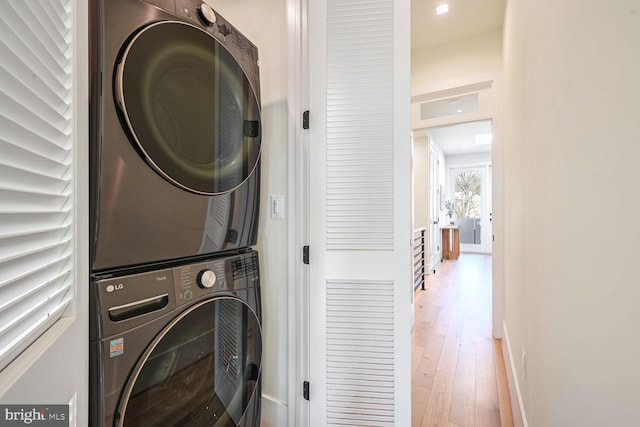 clothes washing area featuring stacked washer / drying machine and hardwood / wood-style floors