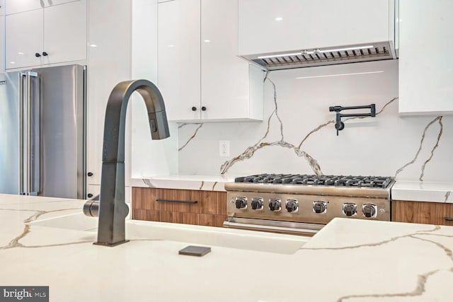 kitchen with white cabinets, light stone counters, and high end refrigerator