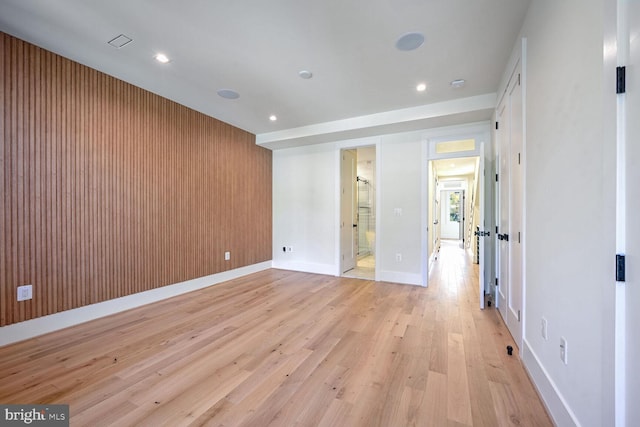 unfurnished room featuring light hardwood / wood-style flooring and wood walls