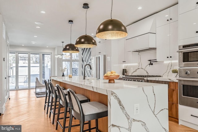 kitchen featuring light stone counters, light parquet floors, and pendant lighting