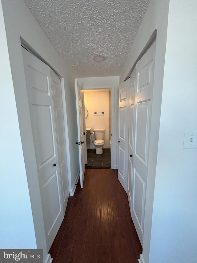 hall with a textured ceiling and dark hardwood / wood-style floors