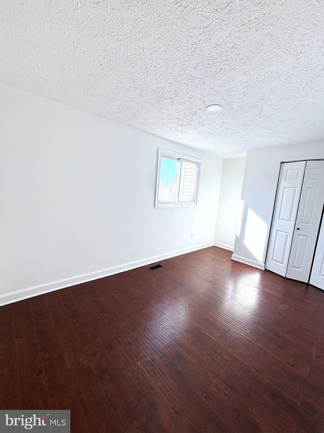 spare room featuring dark hardwood / wood-style floors and a textured ceiling