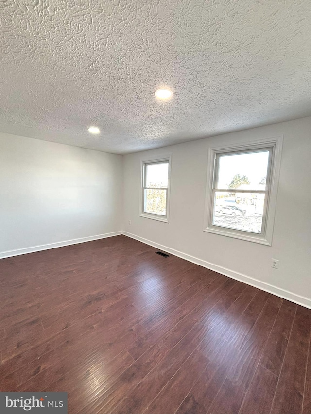 spare room with dark hardwood / wood-style flooring and a textured ceiling