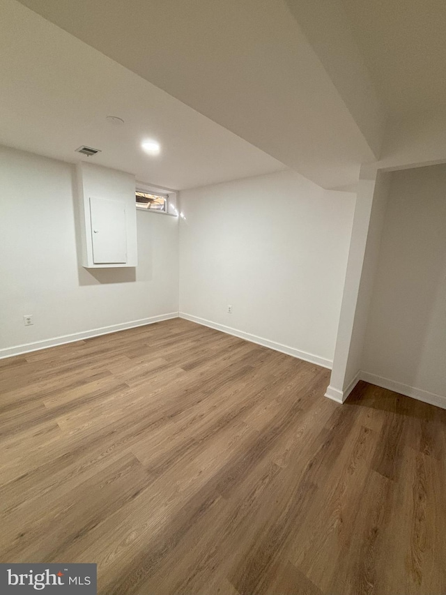 basement featuring hardwood / wood-style floors and electric panel