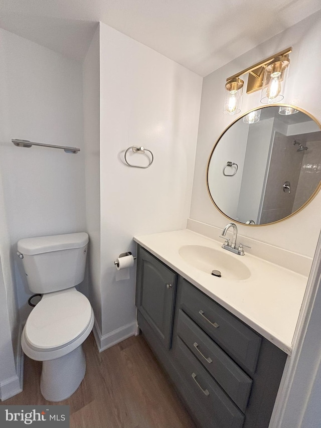 bathroom with hardwood / wood-style flooring, toilet, vanity, and walk in shower