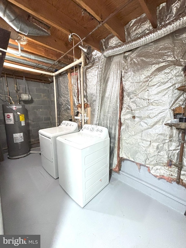 clothes washing area featuring electric water heater and washer and dryer