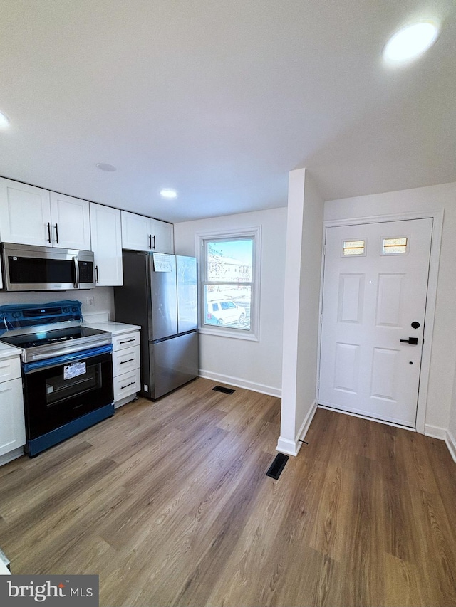 kitchen featuring white cabinets, appliances with stainless steel finishes, and light hardwood / wood-style floors